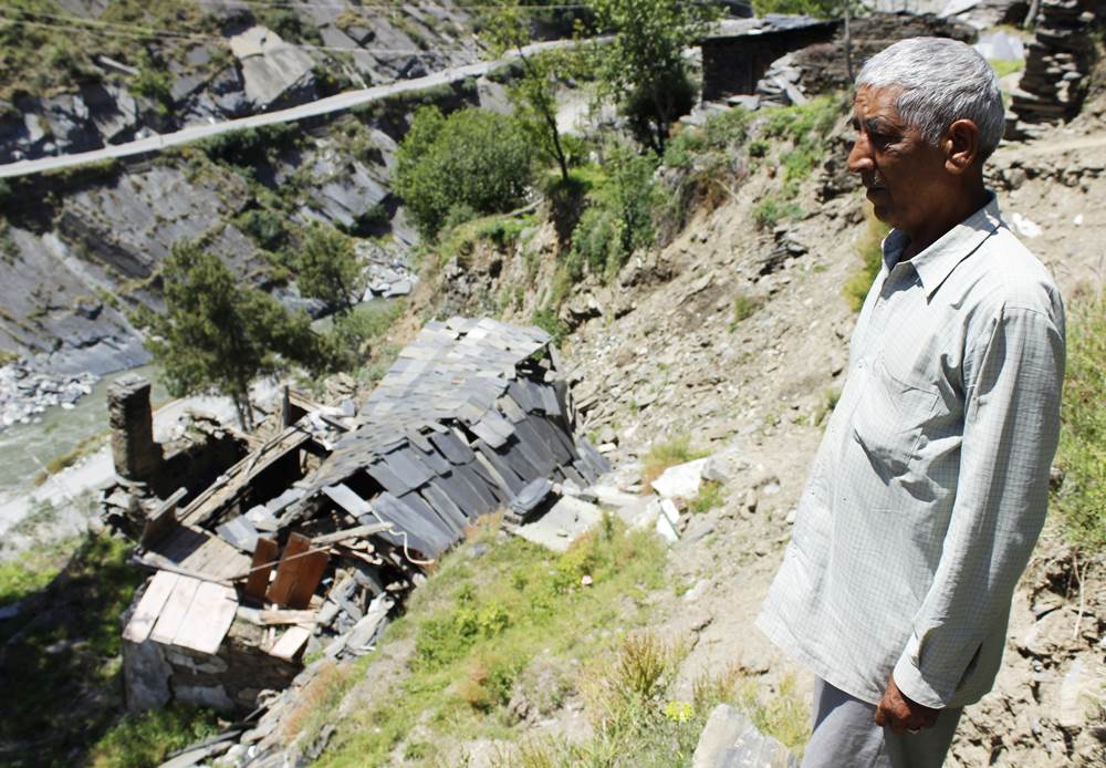4.	Shri Jagdish Sharma standing in front of the debris of his leftover house after the leakage tragedy .